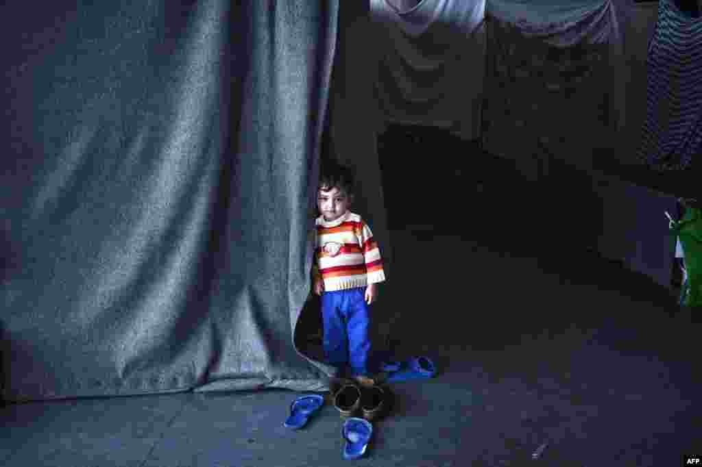 A boy stands by a shelter set up in a hockey arena where mainly Afghan families live at the Hellinikon Olympic Complex in a southern suburb of Athens. (AFP/Louisa Gouliamaki)