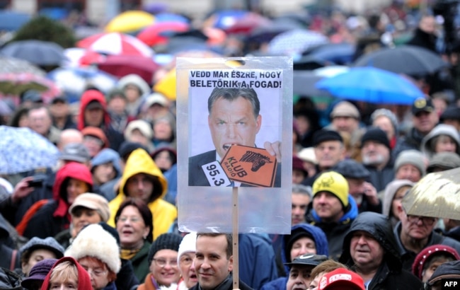 Zaposleni u mađarskoj radio stanici Klubradio i njihove pristalice s plakatom s fotografijom mađarskog premijera Viktora Orbana na kome piše: "Zar ne vidiš da je previše?" na protestu za slobodu govora u Budimpešti 24. februara 2013.