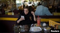 O femeie din Iran își folosește telefonul într-o cafenea din Teheran (fotografie de arhivă). 