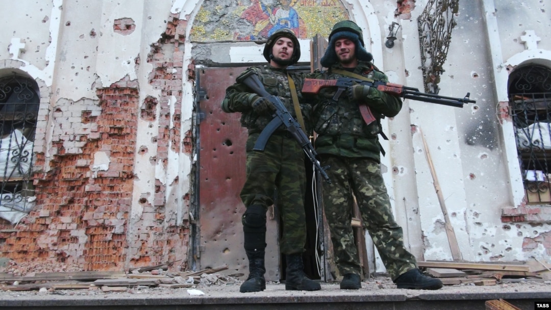 Members of the separatist "Somalia" Battalion pose outside a church riddled with bullets in Donetsk on November 13.