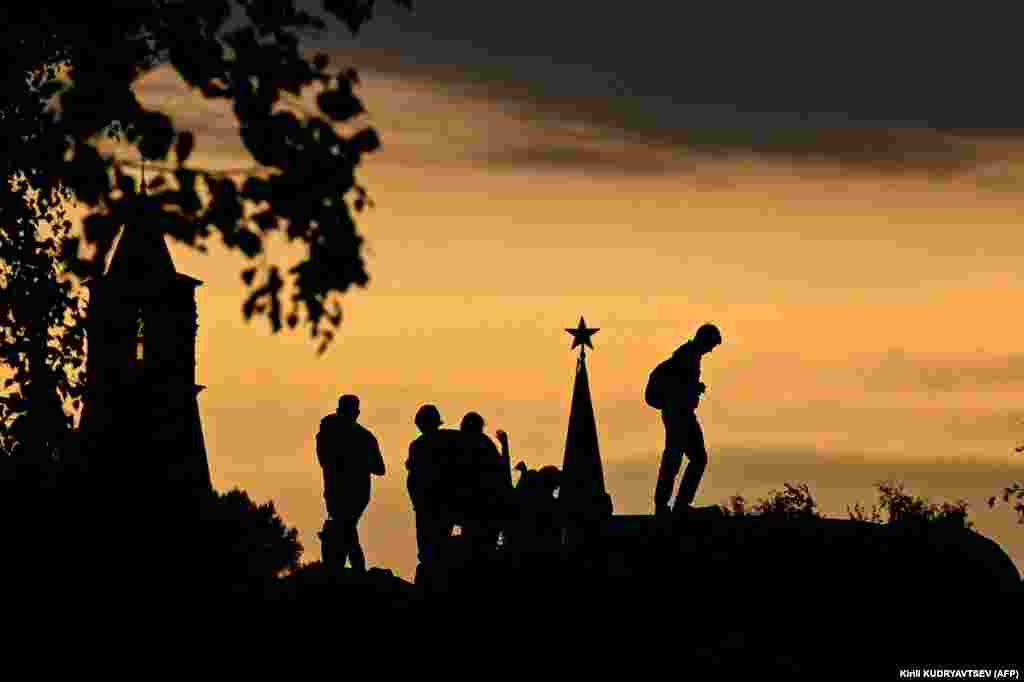 People walk in Zaryadye Park in front of the Kremlin&#39;s Spasskaya Tower during sunset in downtown Moscow.&nbsp;