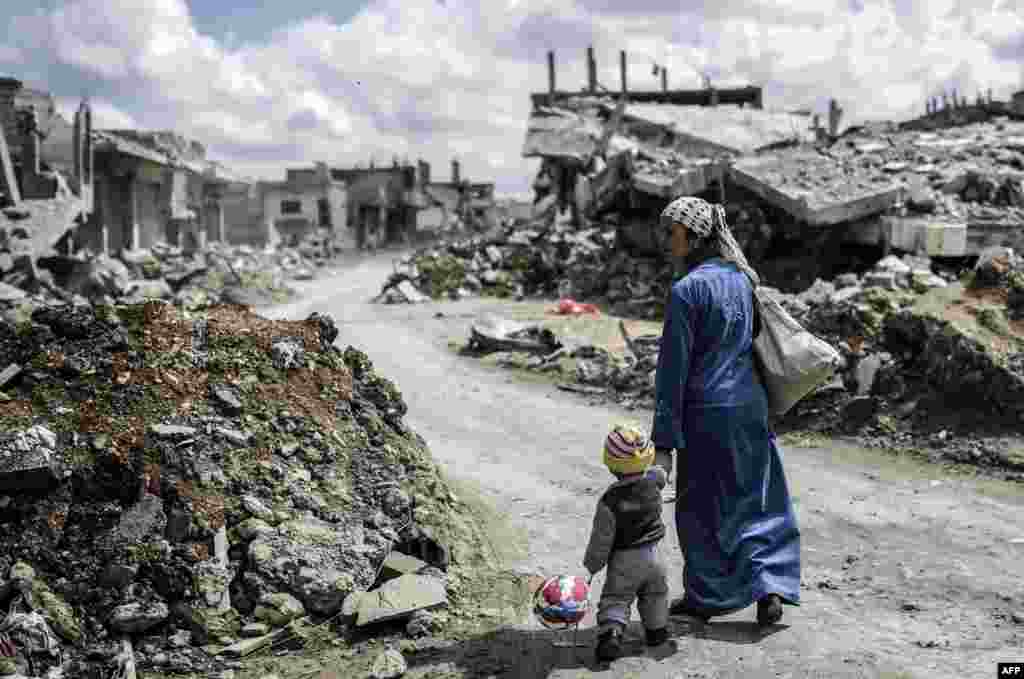 A Kurdish Syrian woman walks with her child past the ruins of the town of Kobani, Syria, March 25, 2015. A six-month siege of the town by the Islamic State militant group was ended in March by Kurdish and allied forces. (AFP/Yasin Asgul)