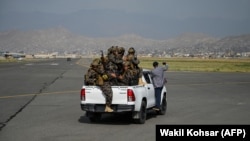 Taliban fighters ride on a vehicle on the runway of the airport in Kabul on August 31. 