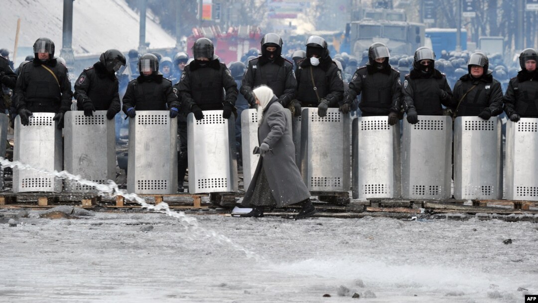 A woman walks in front of riot police on Hrushevskyy Street in central Kyiv.