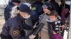 A Macedonian police officer checks a woman and her child with a metal detector near the Macedonian town of Gevgelija after they crossed the border from Greece on March 2.