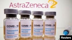 Vials with a sticker reading "COVID-19 / Coronavirus vaccine / Injection only" and a medical syringe are seen in front of a displayed AstraZeneca logo. October 31, 2020. 
