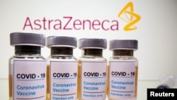 Vials with a sticker reading, "COVID-19 / Coronavirus vaccine / Injection only" and a medical syringe are seen in front of a displayed AstraZeneca logo, October 31, 2020.