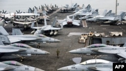 A US Navy officer walks past fighter jets sitting on the flight deck of the Nimitz-class aircraft carrier USS Abraham Lincoln. (file photo)