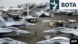 Një oficer i marinës amerikane ec pranë avionëve luftarakë në aeroplanmbajtësin, USS Abraham Lincoln. (Fotografi nga arkivi)