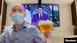 Într-un bar din Franța, urmărind discursul președintelui Emmanuel Macron care a anunțat limitarea accesului în locuri publice numai pentru cei vaccinați, imuni natural la Covid sau cu un test negativ, 12 iulie 2021.