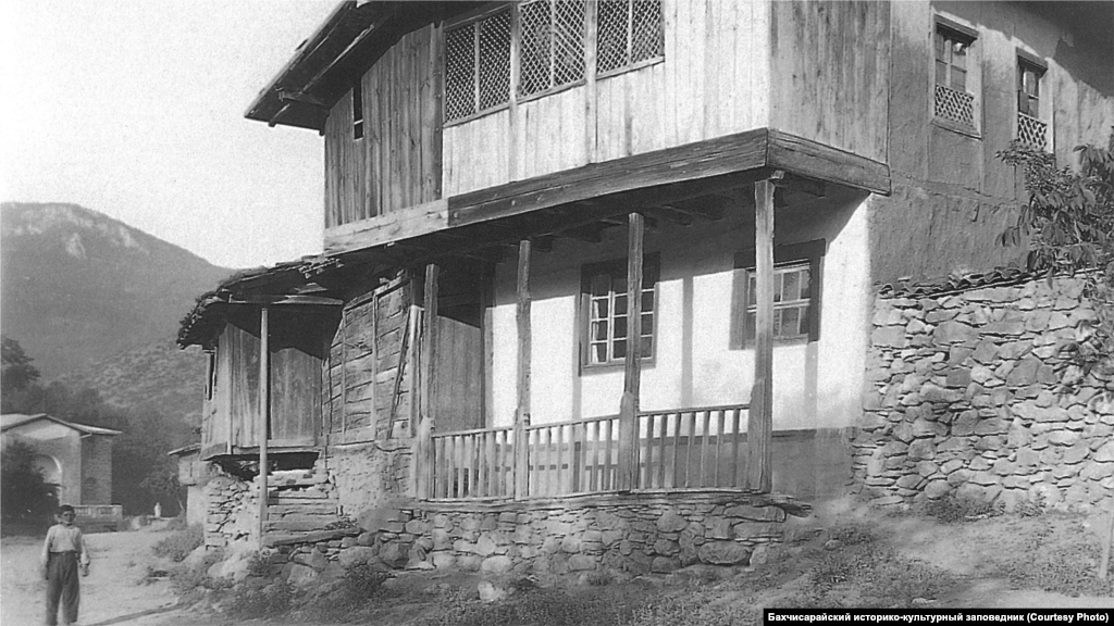 Çöldeki ev. Qırımnıñ cenübiy-ğarbi, 1920 seneleri. Baş odada bacaqlı açıq ocaq ve asılğan qazan bar edi. Divarlar boyu minderler ve yastıqlar, masalar tura edi. Divarlarnı yaraştırmaq içün duvarbezler qullanılğan edi, yerlerde kilimler bar edi