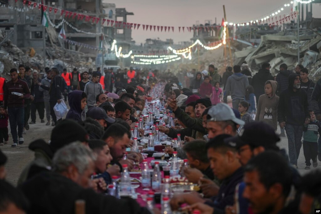 Palestinezët e ulur në një tryezë të madhe për iftar, mes rrënojave të shtëpive dhe ndërtesave të shkatërruara në Rafah, në jug të Rripit të Gazës.