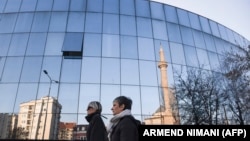 KOSOVO - Two women walk past the Kosovo's parliament building with a mosque reflected in its windows in the capital Pristina, February 13, 2017. 