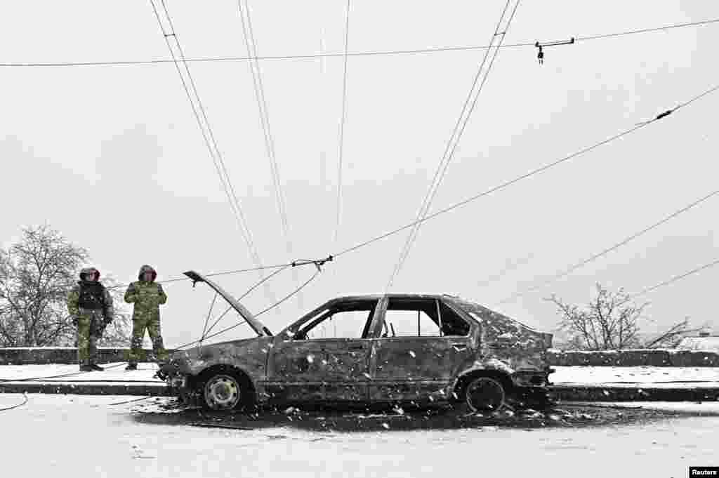 Слідчі стоять біля автомобіля, знищеного внаслідок російського ракетного удару в Запоріжжі