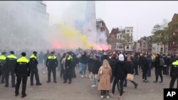 На цьому зображенні, взятому з відео, поліція стоїть на варті, коли вболівальники Маккабі запалюють факели на площі Дам в Амстердамі, Нідерланди, 7 листопада 2024 року