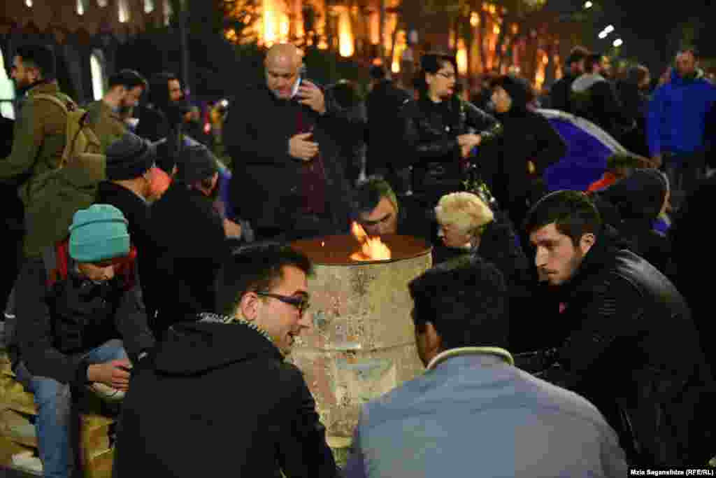 15 ნოემბერს ქუჩაში ჯერ არ ყინავს, მაგრამ ხალხი მაინც&nbsp; კოცონთან თბება.