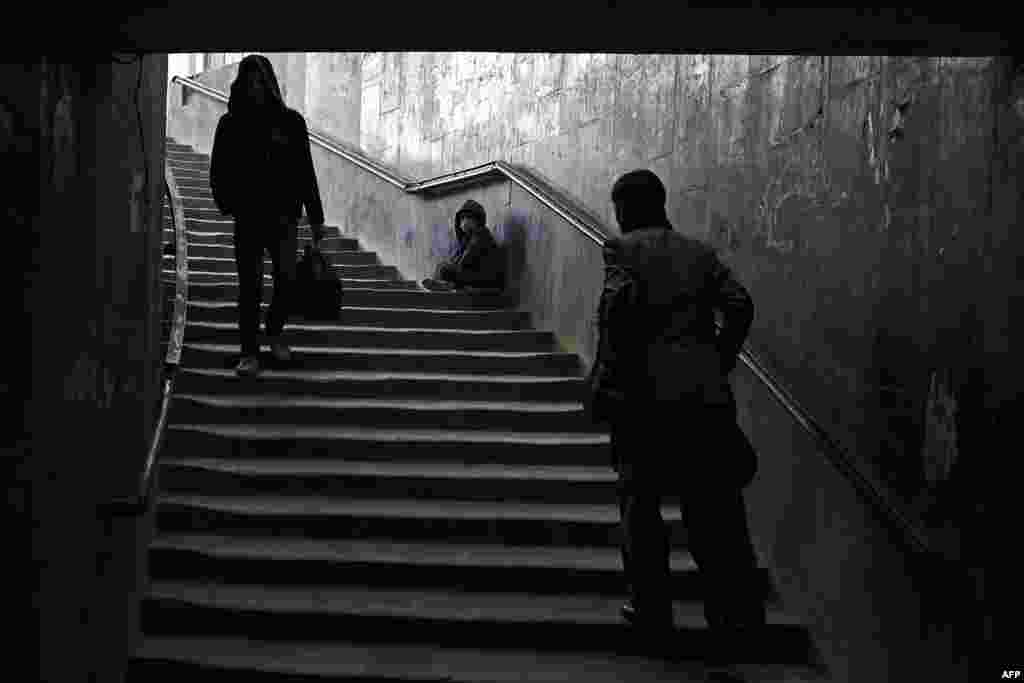 Afghan pedestrians walk past as a young beggar asks for alms in Kabul. (AFP/Wakil Kohsar)