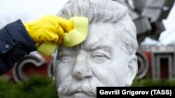 Un voluntar curăță bustul lui Stalin din parcul artelor „Muzeon” din Moscova