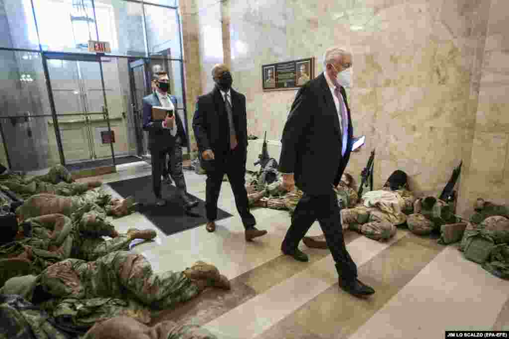 Liderul majorității democrate din Camera Reprezentanților, Steny Hoyer (dreapta), trecând pe lângă membrii Gărzii Naționale, care încearcă să tragă un pui de somn, în clădirea Congresului, 13 ianuarie 2021