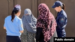 Female police officers in Osh speak to local women during a raid to enforce the niqab ban.