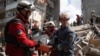 Rescuers carry the body of a person recovered from the debris at the site of an apartment building hit during a Russian missile and drone strike.