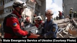 Rescuers carry the body of a person recovered from the debris at the site of an apartment building hit during a Russian missile and drone strike.
