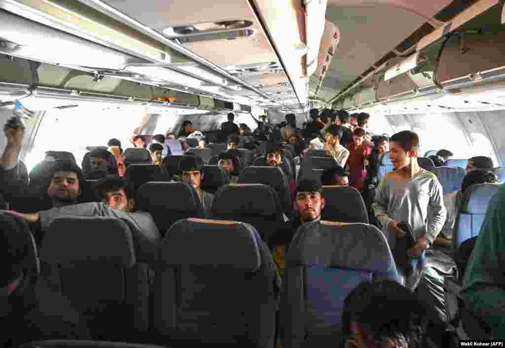 Afghan passengers sit inside a plane as they wait to leave Kabul.