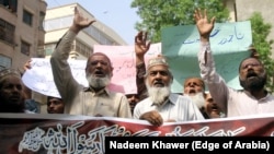 People hold a banner reading in Arabic, 'I will sacrifice my parents for the Prophet's honor,' during a protest to support the man who killed Tahir Nasim, who was accused of blasphemy, inside a court, in Hyderabad, in July 2020.