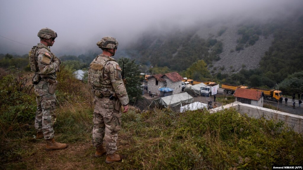 Vojnici KFOR-a na graničnom prelazu Jarinje, između Srbije i Kosova, posmatraju kako lokalno stanovništvo pomera kamione koje su koristili kao barikade na putu