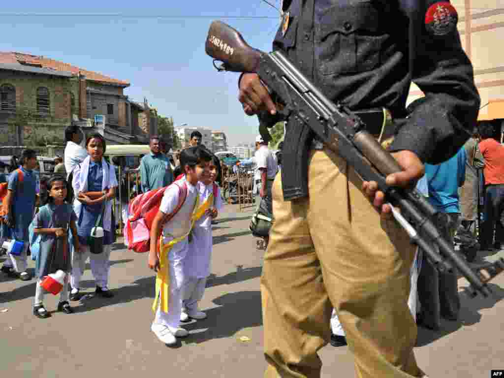 Pakistan -- A Pakistani policeman stands guard as students leave school in Karachi on 26Oct2009 - PAKISTAN, Karachi : A Pakistani policeman stands guard as students leave school in Karachi on October 26,2009. Pakistan partially reopened schools shut nationwide following a suicide attack on a university campus and a spike in Taliban-linked attacks in which nearly 200 people have died this month.