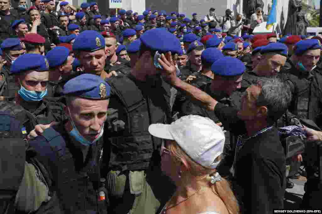 A protester, a former policeman, wipes a young policeman&#39;s forehead during a pensioners protest in front of the parliament building in Kyiv. Pensioners gathered in the Ukrainian capital on July 14 to demand a recalculation and an increase in their pensions.