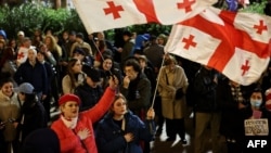Демонстранти развяват грузински знамена, докато участват в протест по повод първата годишнина от оспорваните парламентарни избори. Снимката е от 26 октомври 2025 г.