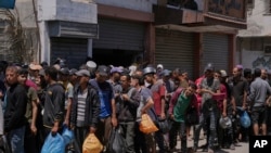 Palestinezët duke pritur në rradhë që të marrin furnizime ushqimore afër një qendre për shpërndarjen e ndihmës në Deir al-Balah më 30 maj 2025. 