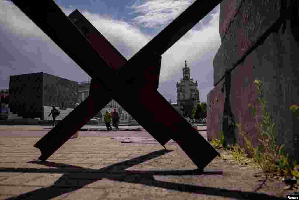 People walk near an anti-tank barrier on Independence Square in the Ukrainian capital, Kyiv.