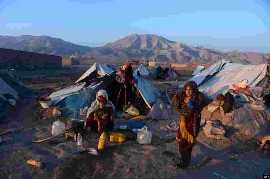 An internally-displaced Afghan woman holds a child as she sits in front of her tent at a refugee camp on the outskirts of Herat. (AFP/Aref Karimi)