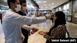 Жительница Тегерана проходит проверку на инфицирование при входе в торговый центр. 3 марта 2020 года