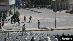 Government backers break a road barrier to reach antigovernment protesters during clashes in Sanaa on February 17.