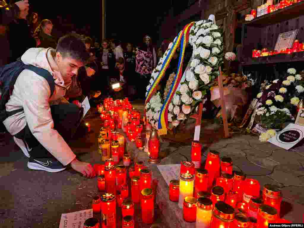 Un tânăr aprinde o lumânare în fața clubului Colectiv, pe 30 octombrie 2025, în timpul unui eveniment de comemorare a celor 65 de victime care au murit în urma incendiului care a avut loc în urmă cu zece ani.