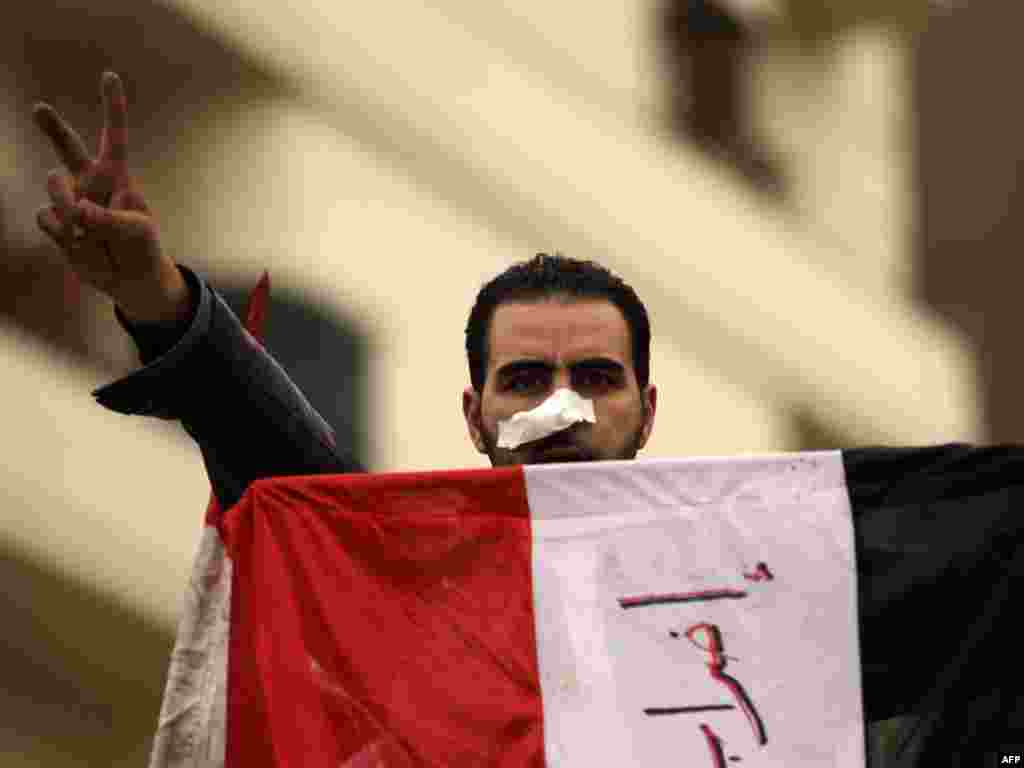 An antigovernment protester flashes the victory sign while holding his national flag in Tahrir Square on February 5.