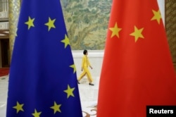 Egy kínai tisztviselő sétál az uniós és kínai zászlók mellett a 2020 végén Brüsszelben folytatott tárgyalások során