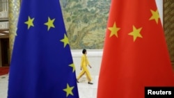Egy résztvevő sétál az Európai Unió és Kína zászlaja előtt egy magas szintű EU–Kína gazdasági tanácskozáson Pekingben 2018. június 25-én