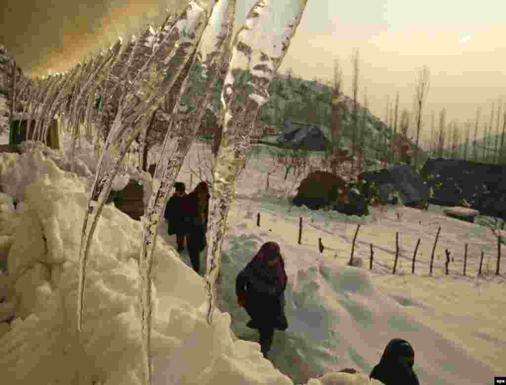 Children walk past the icicles hanging from the roof of a residential house during a sunny day on outskirts of Srinagar, Kashmir. (epa/Farooq Khan)