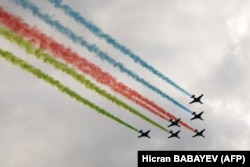 Military aircraft release smoke in the colors of the Azerbaijani flag over Baku.