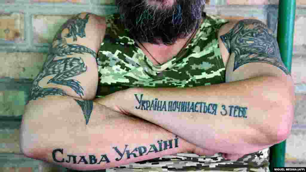 Militar ucrainean arătându-și tatuajele de pe brațe: &bdquo;Slavă Ucrainei&rdquo; (stânga) și&nbsp;&bdquo;Uckraina începe cu tine&rdquo; (dreapta), regiunea Donețk.