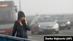 A woman walks through the smog-covered streets of Belgrade.