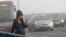 A woman walks through the smog-covered streets of Belgrade.