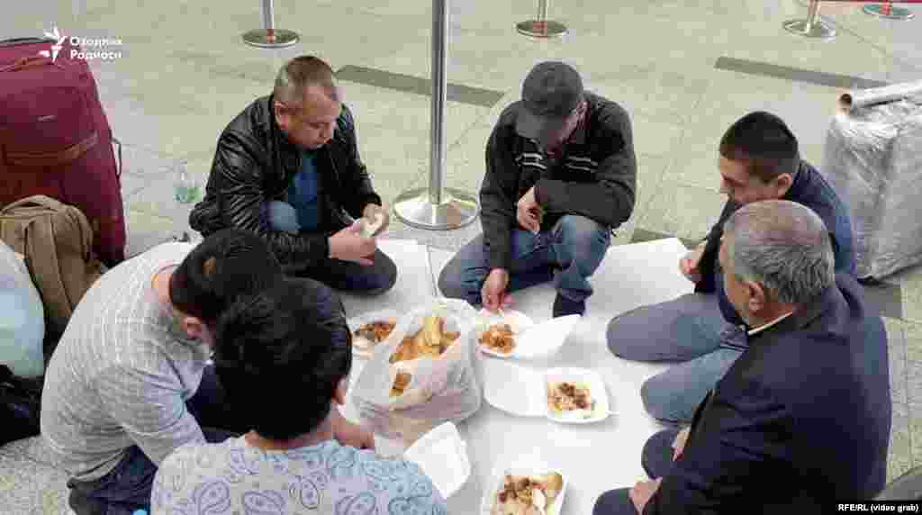 Uzbeci care iau masa pe podea, în aeroportul Vnukovo, pe 28 martie.