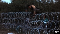 Migrants of several countries jump over a blade iron fence at the Hungarian-Serbian border near the village of Roszke on August 30.