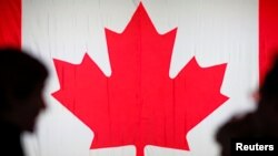 CANADA - People are silhouetted in front of the Canadian national flag at the Palais des Congres in Montreal, October 21, 2019.