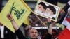 A Hezbollah supporter chants slogans, as he holds a picture of the late Iran revolutionary founder Ayatollah Khomeini, left, and Iran's Supreme Leader Ayatollah Ali Khamenei, right, during a Hezbollah-organized rally titled "in solidarity with oppressed Y